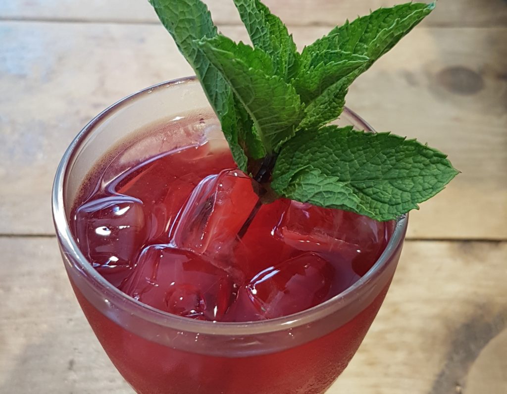apple and mint iced tea in a glass with a sprig of mint